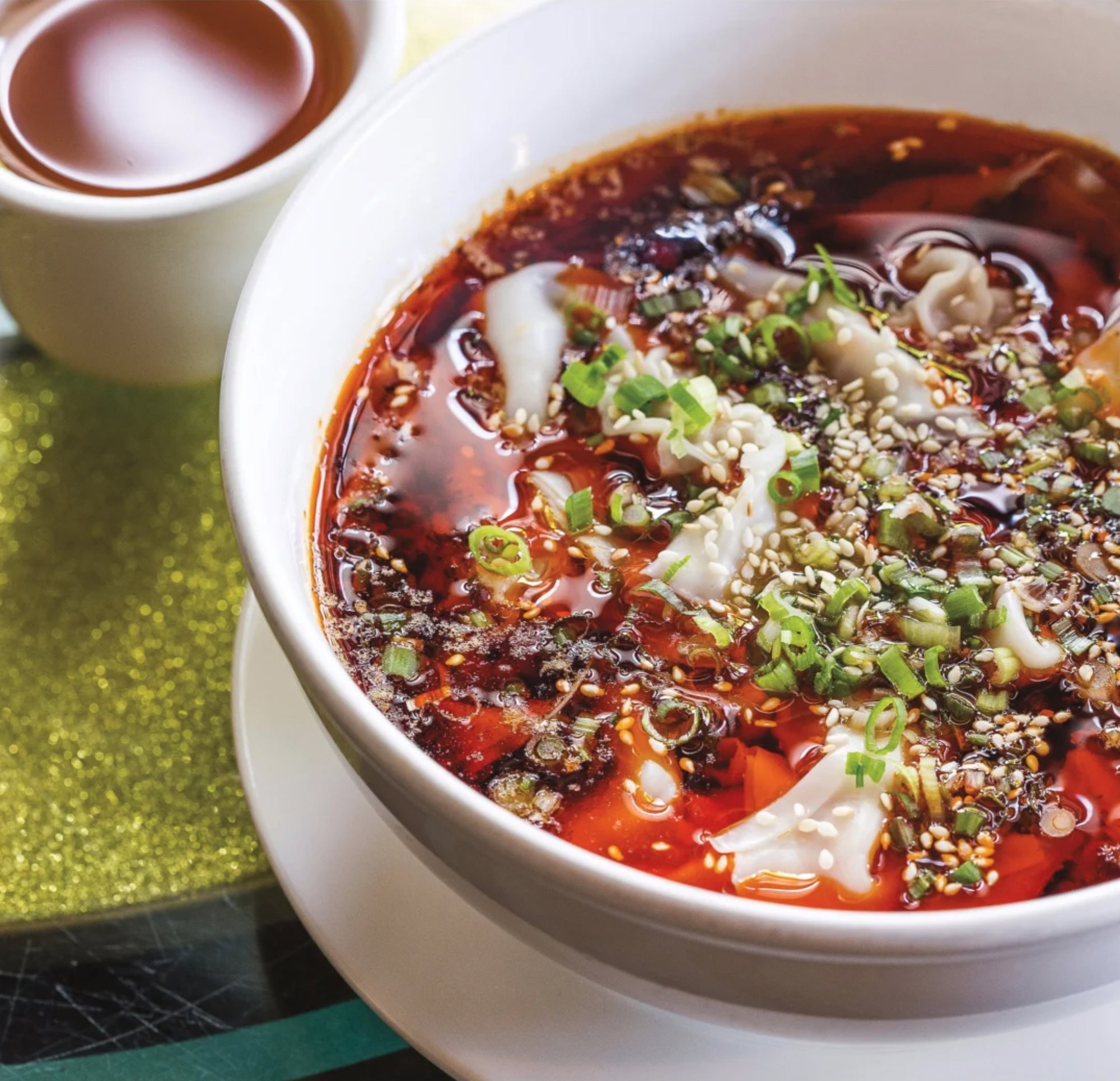 Plump white wontons float in a glimmering pool of red chile oil.