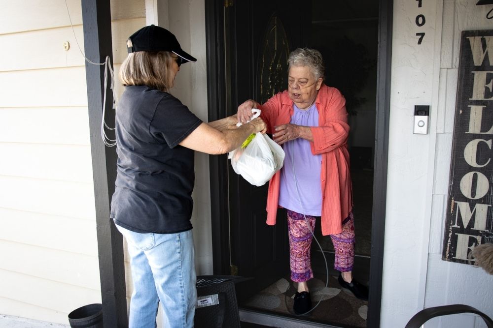 Volunteer Sally Galligan delivers meals to Sheena, 79, helping her stretch her limited grocery budget while bringing a familiar, friendly face to her door. Photo by Nicole Ceron.